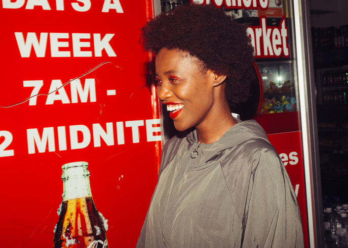 Cheerful black woman near advertising in supermarket